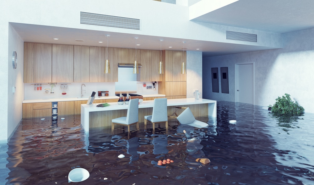 Kitchen flooded with brown water, submerged furniture, and debris scattered on the floor.